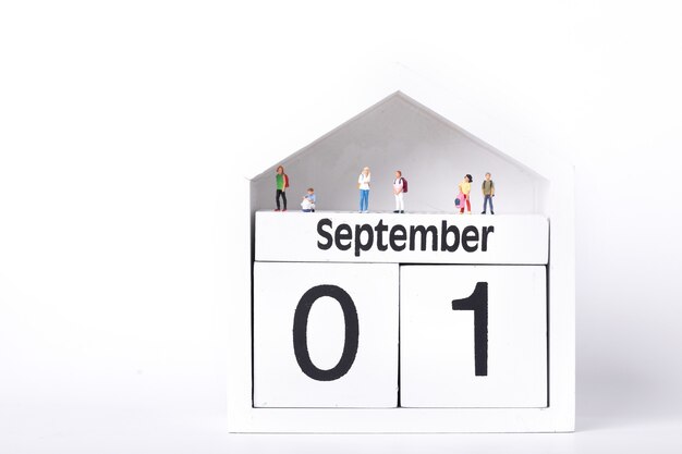 Figuras de estudiantes de pie sobre un calendario que representa el primero de septiembre