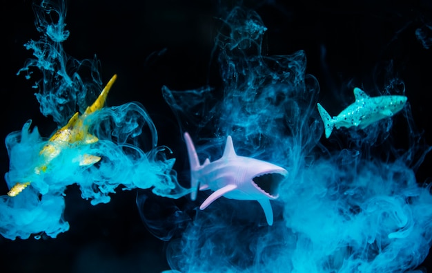 Figuras de tiburón en agua con efecto negativo y humo azul.