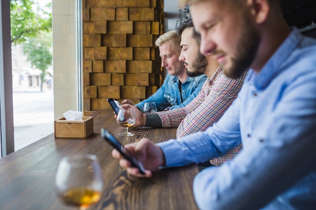 Foto gratuita fila de amigos varones usando sus móviles en el restaurante