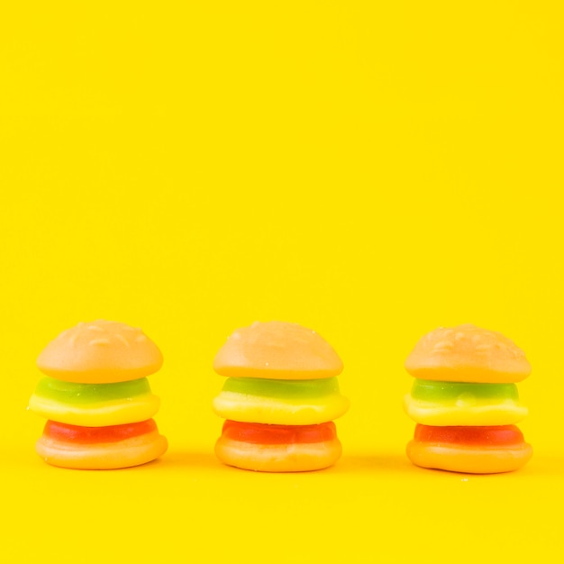 Fila de los caramelos coloridos de la hamburguesa en fondo amarillo