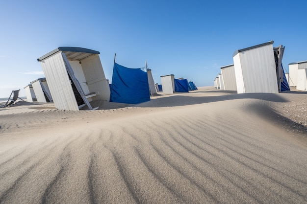 Fila de casilleros blancos individuales y vestidores en una playa de arena