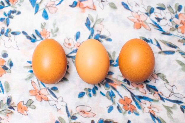 Foto gratuita fila de huevos de gallina en material floreado