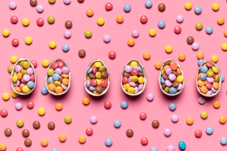 Foto gratuito fila de los huevos de pascua quebrados con los caramelos de la gema en el contexto rosado