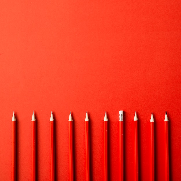 Fila de lápices afilados rojos sobre fondo rojo
