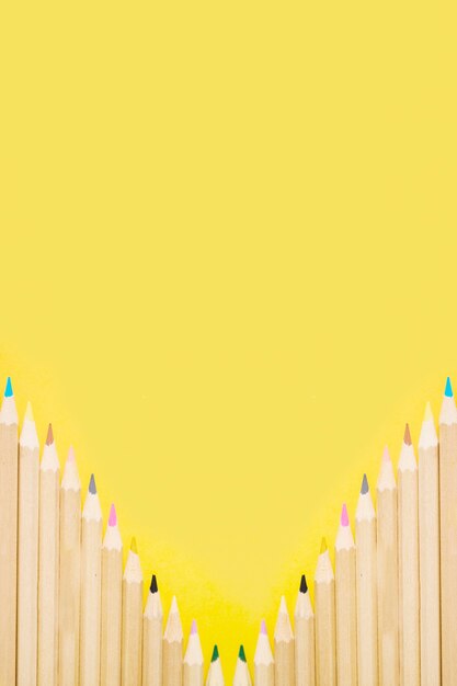 Fila de lápices de colores sobre fondo amarillo