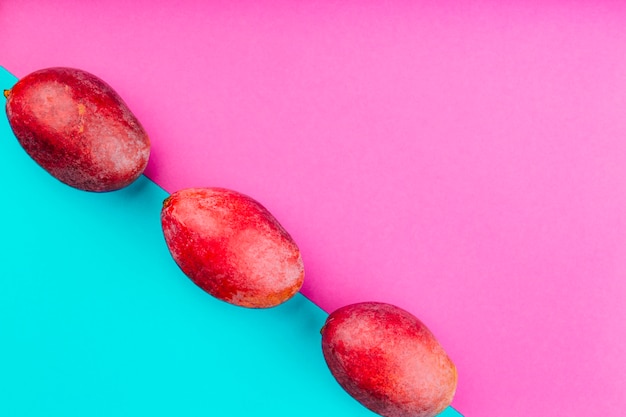 Fila de mangos rojos sobre doble fondo rosa y azul