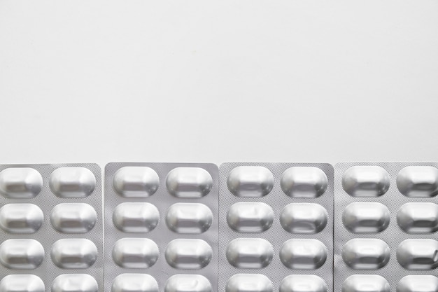 Fila de píldoras de paquete de ampolla de plata aisladas sobre fondo blanco