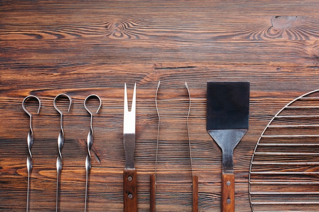 Foto gratuita fila de utensilios de barbacoa en mesa de madera