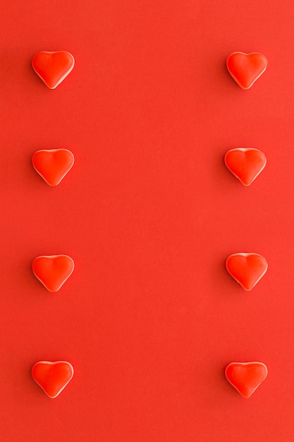 Foto gratuita filas de caramelos de forma de corazón sobre fondo rojo