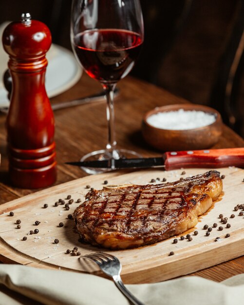 Filete aseado en un soporte de madera con una copa de vino tinto