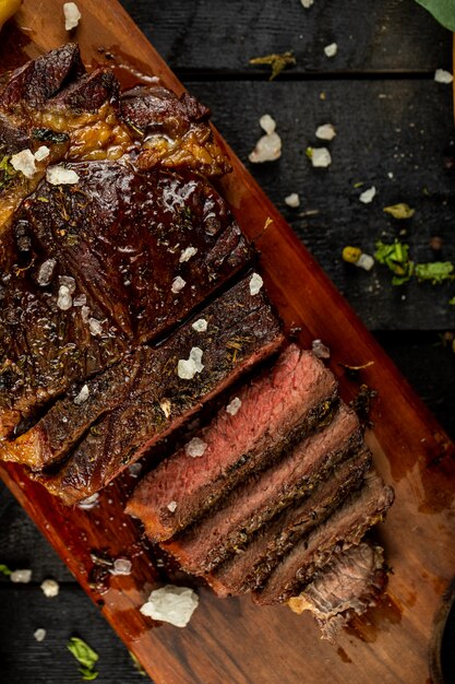 Filete de carne cruda cocida en rodajas y sal agregada, servida en la mesa negra