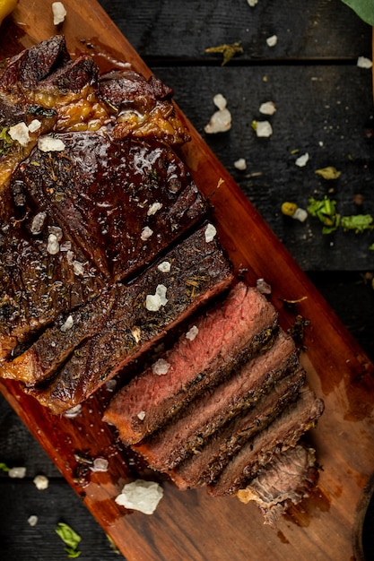 Filete de carne cruda cocida en rodajas y sal agregada, servida en la mesa negra