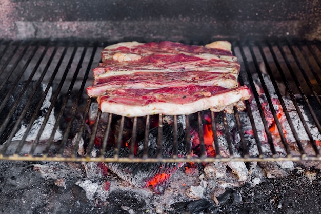 Filete de carne cruda fresca en la hoja de metal cocida sobre el carbón quemado