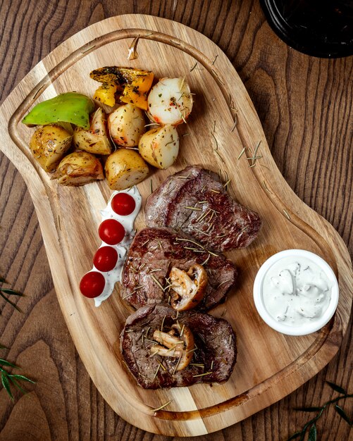 Filete de carne frita con verduras sobre tabla de madera