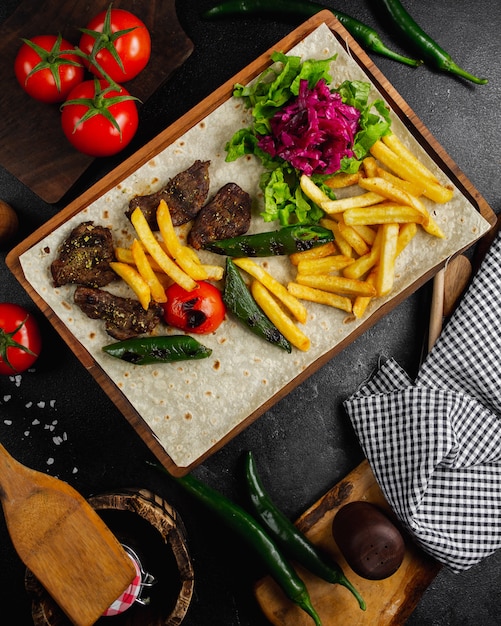 Filete de carne con papas fritas y ensalada de verduras.