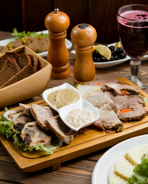 Filete de carne en rodajas y servido con especias, salsas, ensalada verde y una copa de vino tinto.