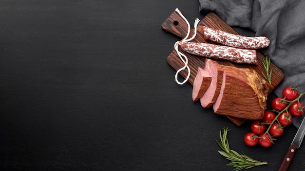 Filete de carne y salami sobre tabla de madera con espacio de copia