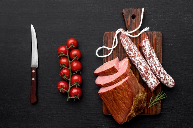 Filete de carne y salami sobre tabla de madera y verduras