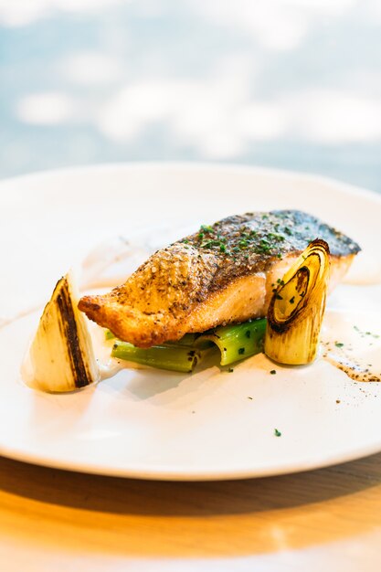 Filete de filete de salmón con salsa en un plato blanco