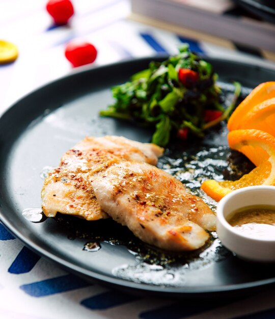 Filete frito con rodajas de naranja y hierbas