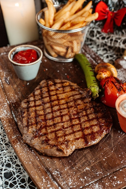 Filete a la parrilla servido con papas fritas ketchup y verduras a la parrilla