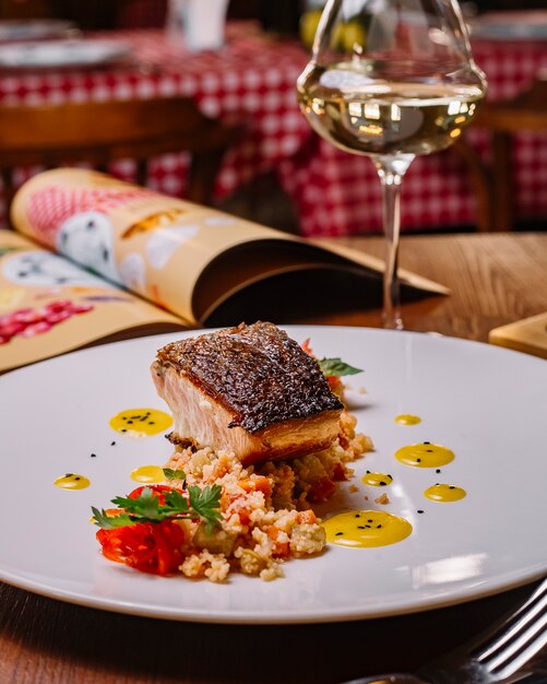 Filete de pescado a la parrilla servido sobre la ensalada de cuscús con pimientos verticales