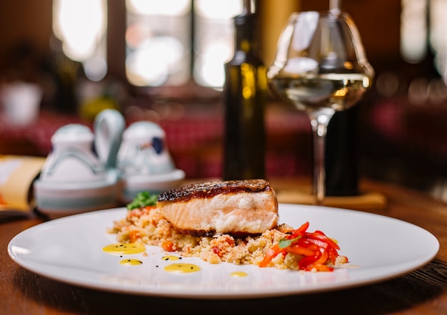 Filete de pescado a la parrilla servido sobre la ensalada de cuscús con pimientos