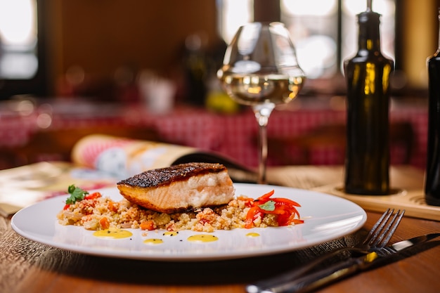 Filete de pescado a la parrilla servido sobre la ensalada de cuscús con pimientos