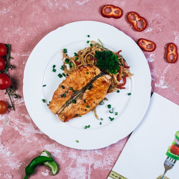 Filete de pescado a la plancha con hierbas y ensalada de verduras. Vista superior.