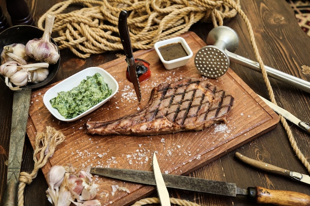 Filete a la plancha sobre la tabla de madera sal de ajo tomate especias vista lateral