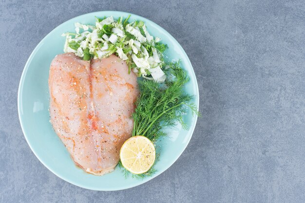 Foto gratuita filete de pollo y limón en placa azul.