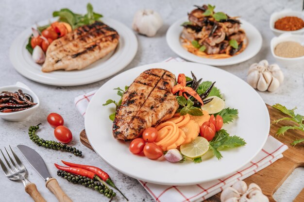 Filete de pollo con limón, tomate, chile y zanahoria en un plato blanco.