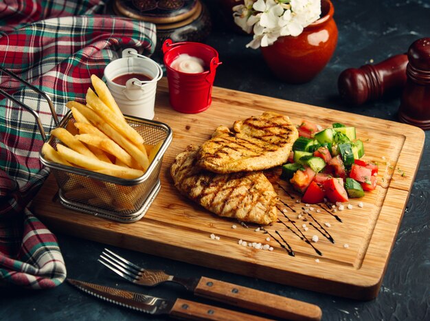 Filete de pollo con papas fritas y ensalada de verduras.