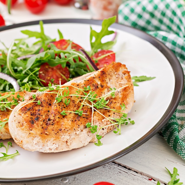 Filete de pollo a la parrilla y ensalada de vegetales frescos de tomate, cebolla roja y rúcula. Ensalada de carne de pollo. Comida sana.