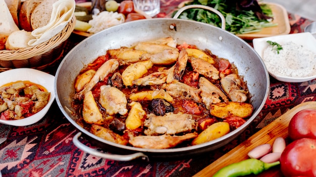 Filete de pollo a la parrilla con papas en salsa de tomate en una sartén de acero inoxidable.