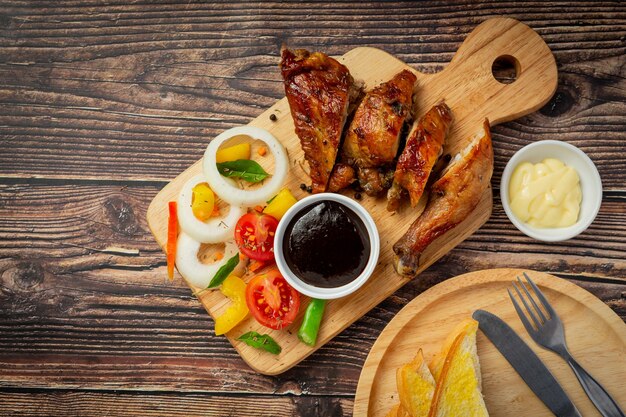 Filete de pollo a la plancha y verduras sobre fondo de madera oscura.