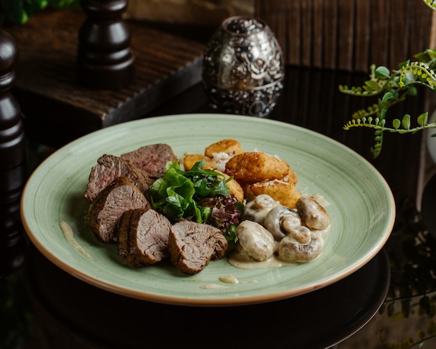 Filete de res finamente cocido con champiñones salteados en una salsa cremosa y papas asadas