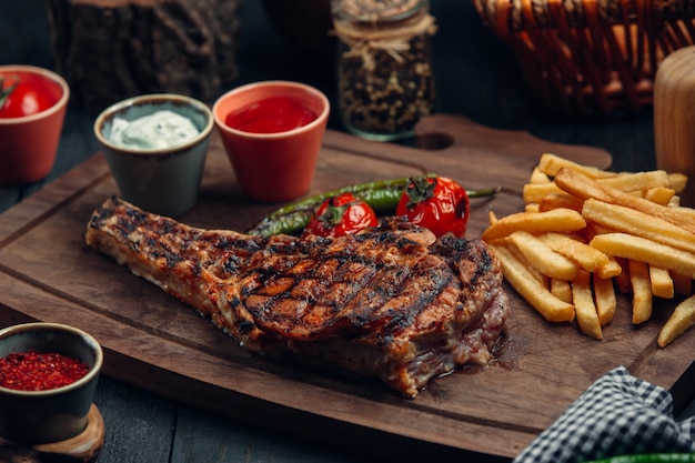 filete de res a la parrilla con papas fritas, tomate a la parrilla, pimientos y salsas