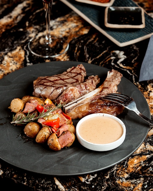 Filete de res a la parrilla servido con plato de papas y salsa de champiñones