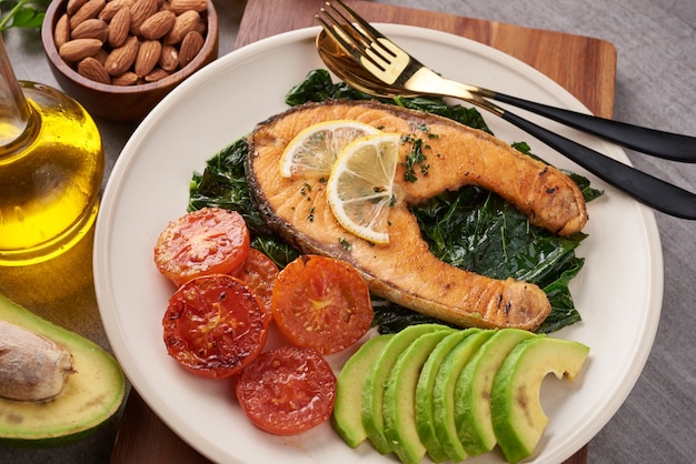 Filete de salmón a la plancha y ensalada de tomate vegetal de lechuga verde fresca con guacamole de aguacate. Concepto de nutrición equilibrada para una dieta mediterránea flexitariana de alimentación limpia.