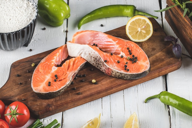 Filete de salmón sobre tabla de madera con limón y tomate con chiles verdes