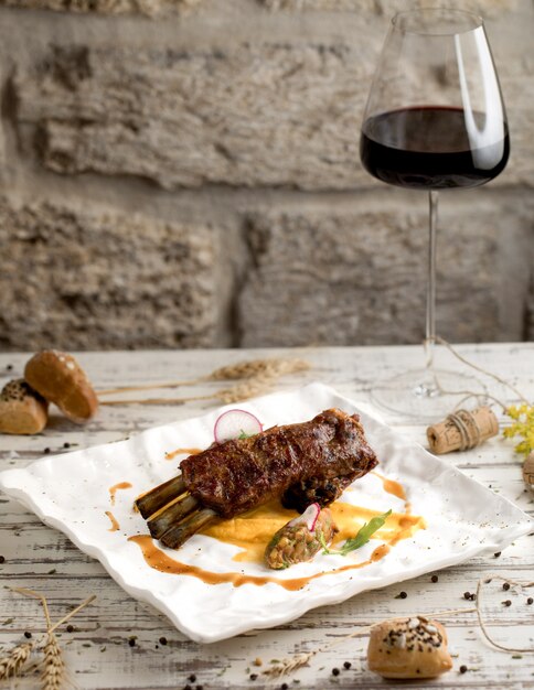 Filete de ternera con salsa y una copa de vino tinto en un plato blanco.