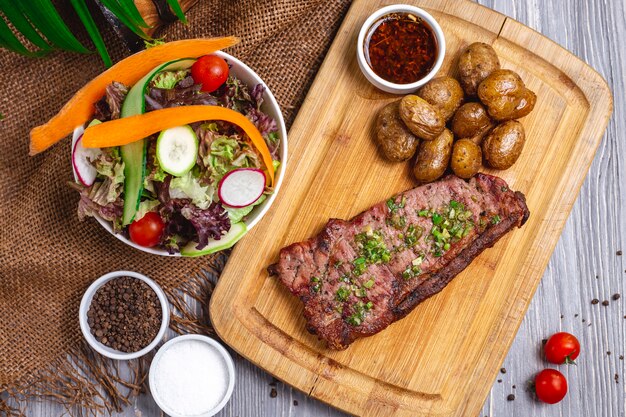 Filete de vista superior con papas al horno y ensalada de verduras