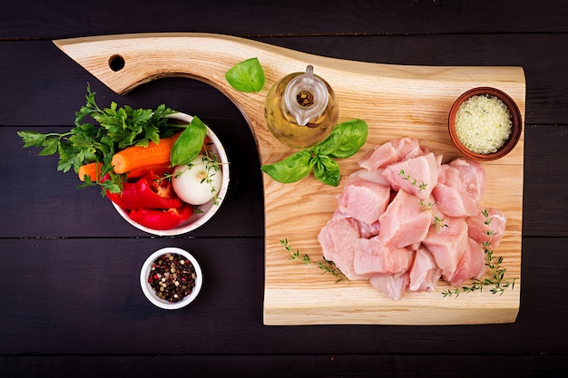 Filetes de pechuga de pollo cruda en tabla de cortar de madera con hierbas y especias. Vista superior