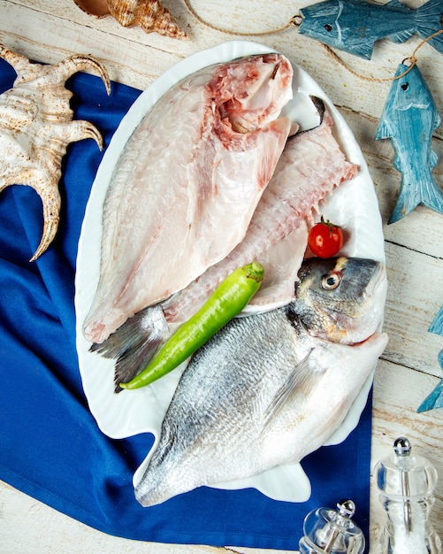 Foto gratuita filetes de pescado a la mitad servidos en un plato con pimiento y tomate