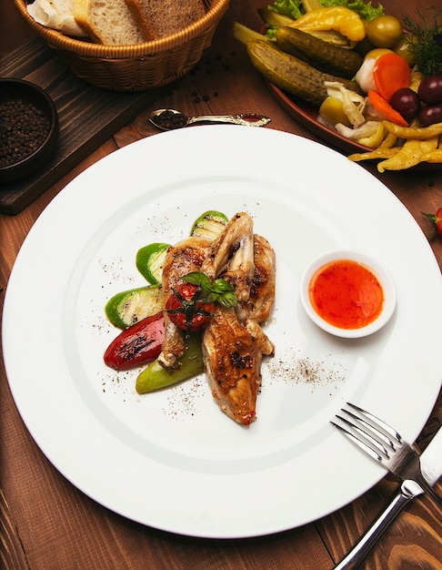 Filetes de pollo a la parrilla, asados y verduras en un plato blanco con salsa