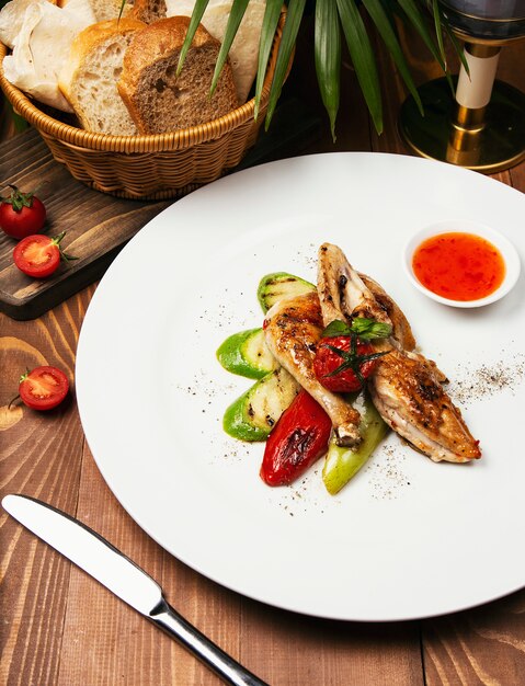 Filetes de pollo a la parrilla, asados y verduras en un plato blanco con salsa