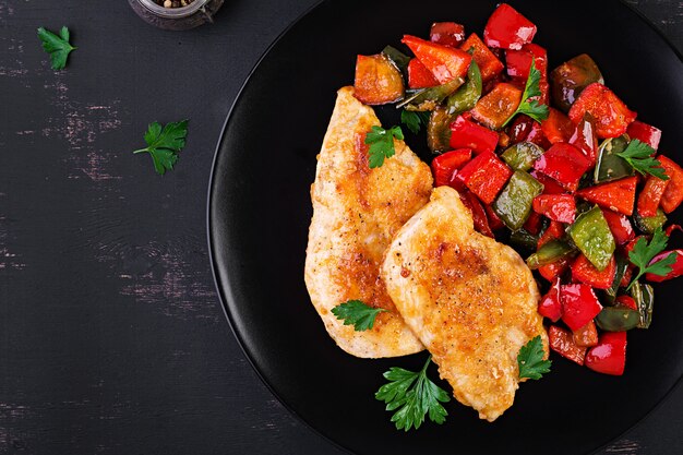 Filetes de pollo a la parrilla y pimiento dulce en un plato negro