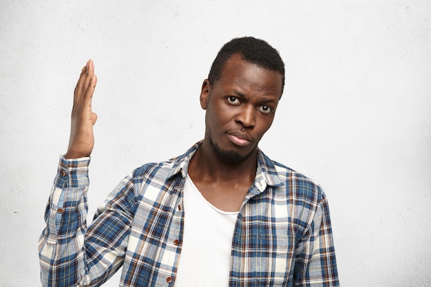 Foto gratuita filmación en interiores de incomprendido joven afroamericano vistiendo camisa a cuadros