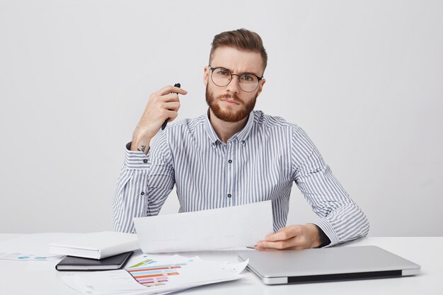 Filmación en interiores del jefe o empleador masculino joven estricto seguro, tiene peinado y barba de moda